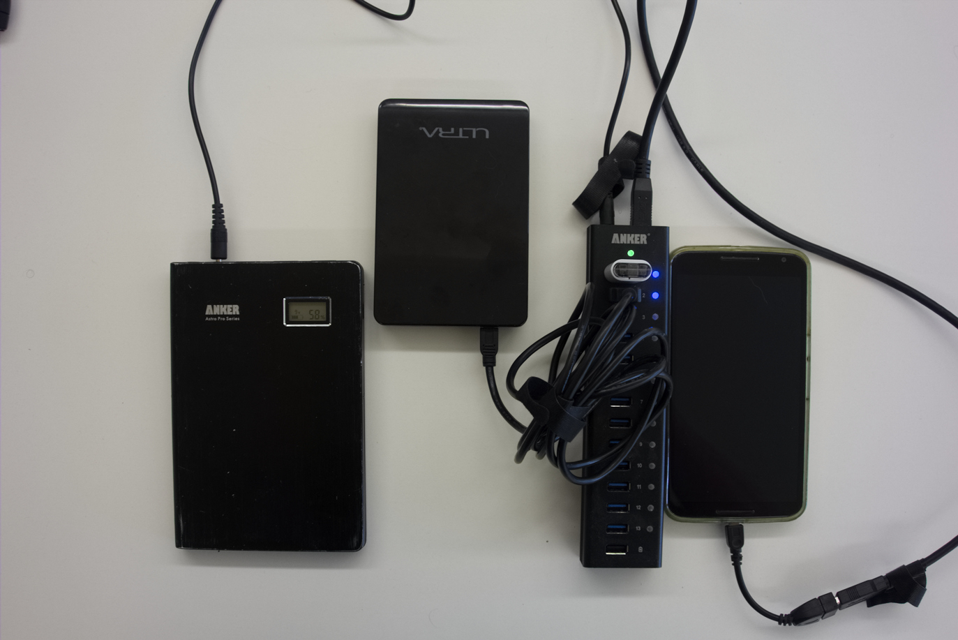 An external battery pack powering a USB hub with a disk drive, a flash drive, and a phone plugged into it.