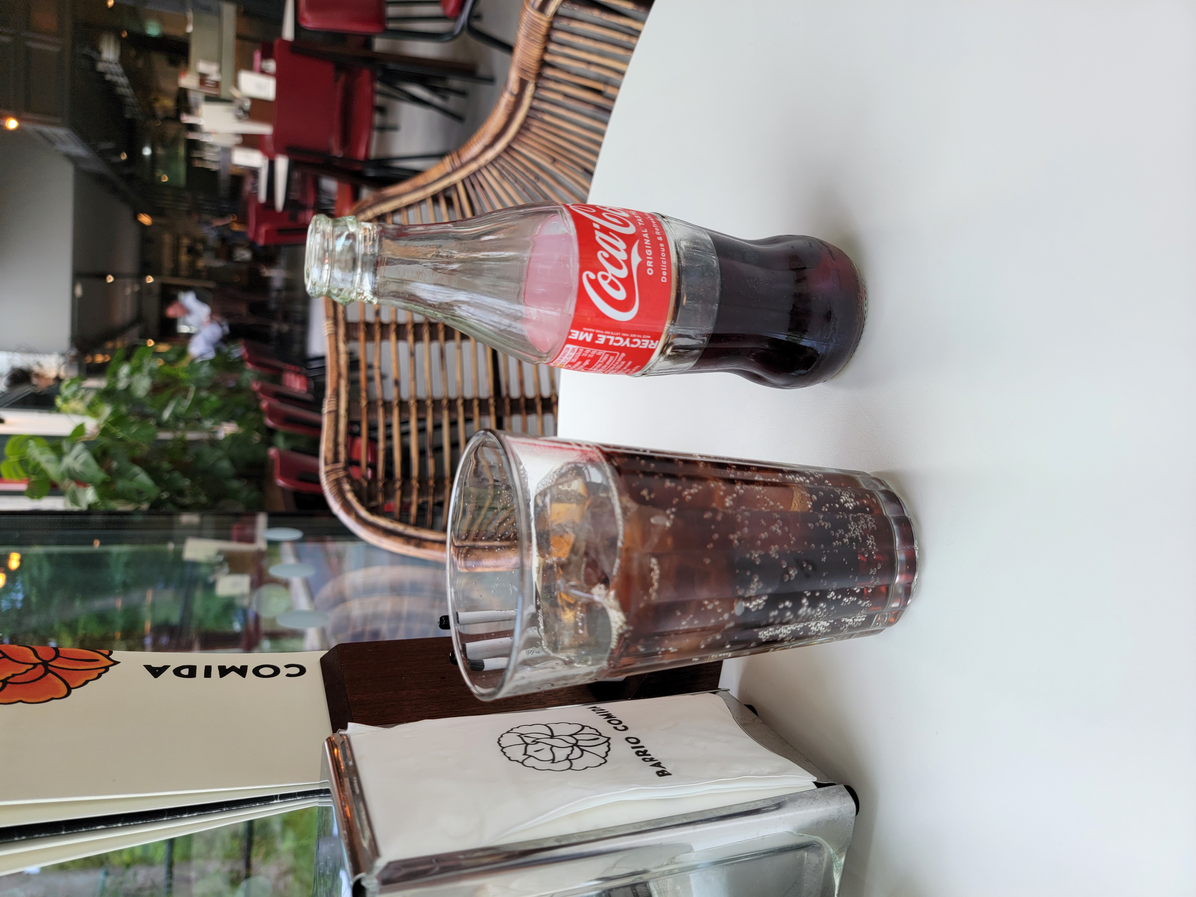 A glass bottle of coca-cola alongside a full glass.